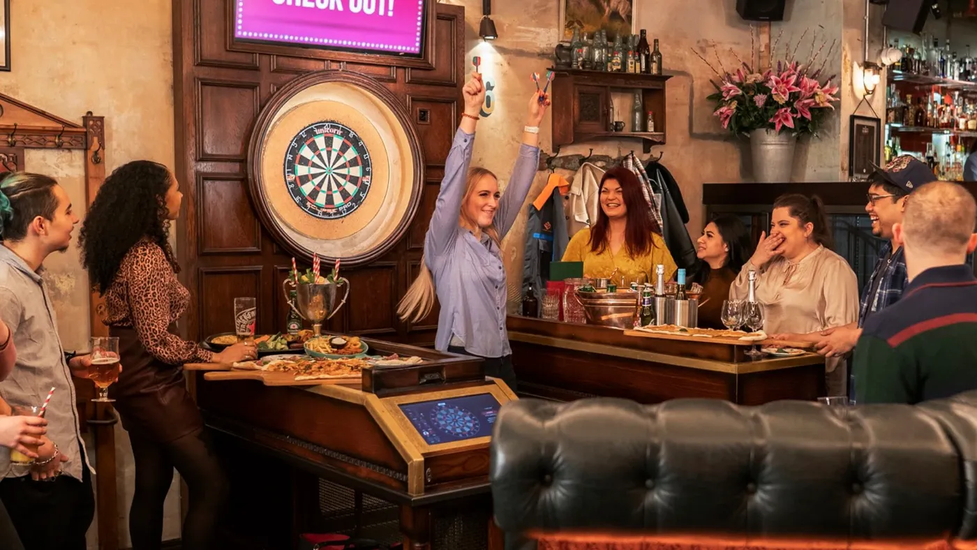A group of people playing darts at a team event in Flight Club