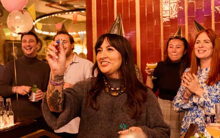 A group of people playing darts at a birthday party in Flight Club