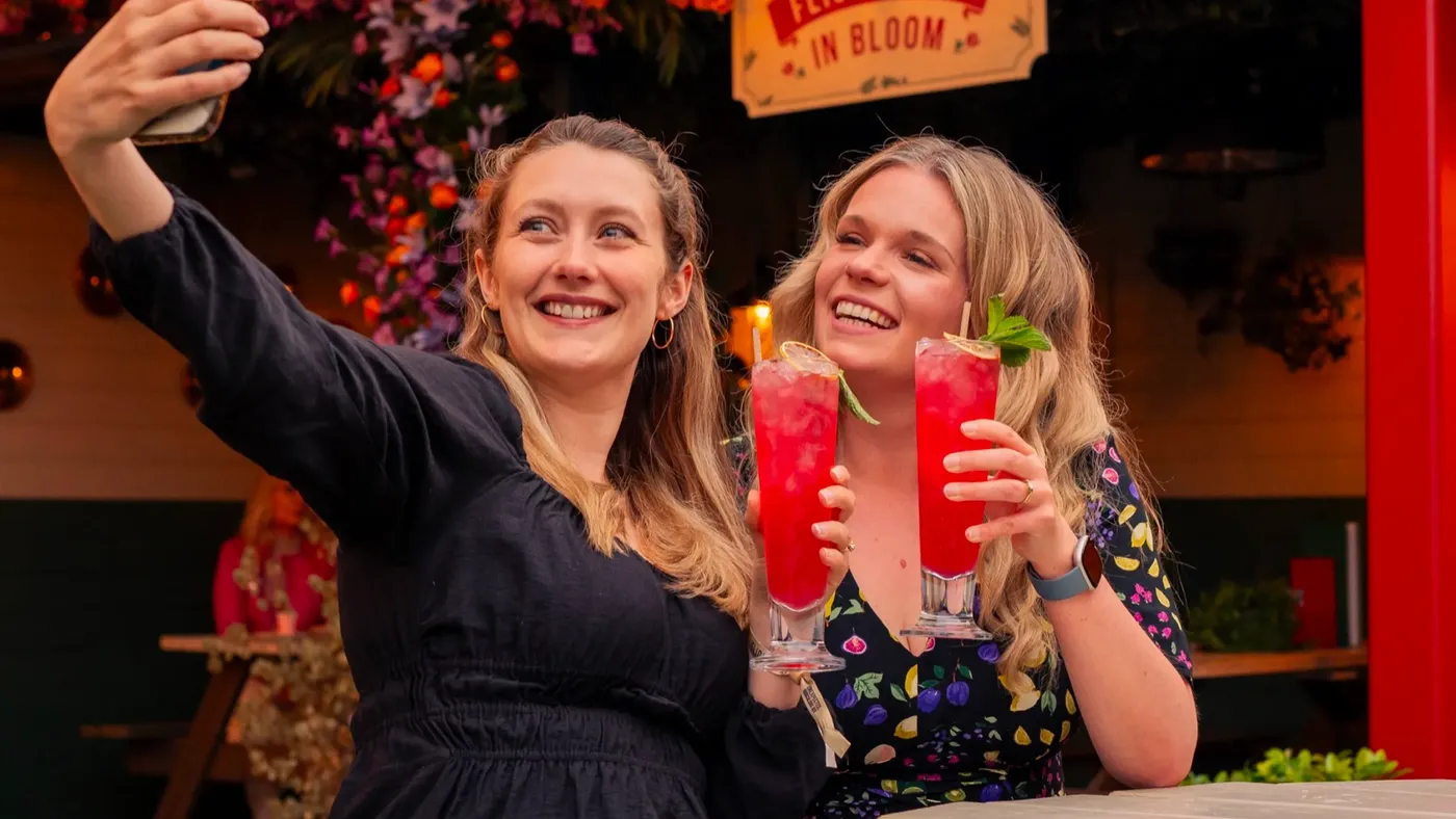 Two people taking a selfie with cocktails