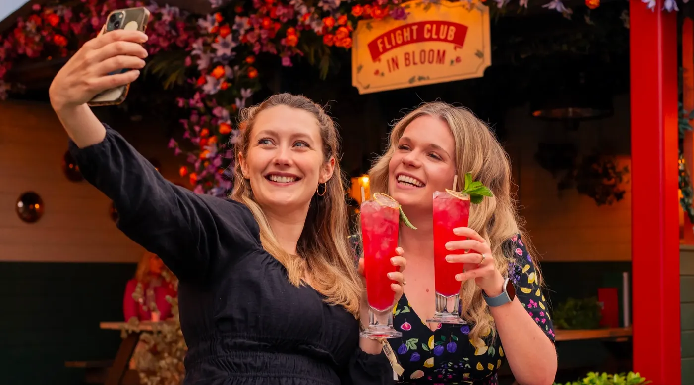 Two people taking a selfie with cocktails