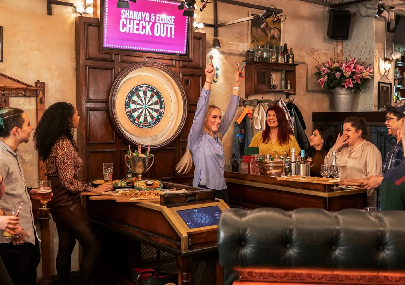 A group of people playing darts at a team event in Flight Club